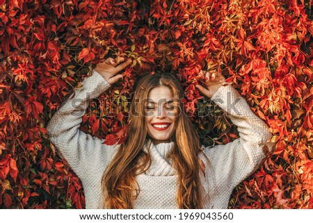 Young happy woman upon a wall of red ivy leaves. Royalty-Free Stock Photo #1969043560