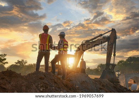 Construction engineers supervising progress of construction project stand on new factory,Engineering Consulting People on construction site holding blueprint in his hand. Building inspector.  Royalty-Free Stock Photo #1969057699