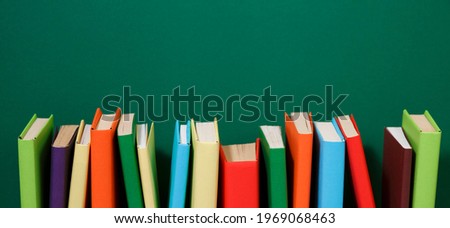 Composition with vintage old hardback books, diary, fanned pages on wooden deck table and colored background. Books stacking. Back to school. Copy Space. Education background. Royalty-Free Stock Photo #1969068463