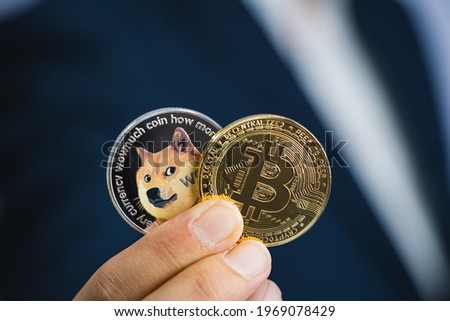 Golden bitcoin Dogecoin DOGE group included with Cryptocurrency on hand business man wearing a blue suit. Filed and put and give to me. Close up and Macro photography concept. Royalty-Free Stock Photo #1969078429