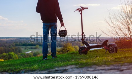 Modern eco-friendly transport electric scooter. A male rider on an electric scooter enjoys nature on the observation deck of the city, a beautiful forest landscape. Urban transport. Royalty-Free Stock Photo #1969088146