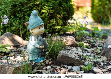 A gnome in the garden. Decorative sculptures. Landscape decor. A stone in the garden. Green garden. Sculpture of a man.