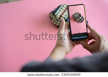 Men take photos of hats with their mobile phones or digital cameras on smartphones to post for sale online on the Internet.