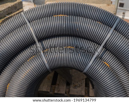 black flexible drainage pipes, not yet installed, on a construction site

