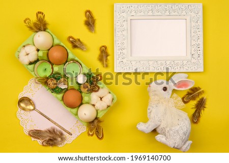 Light vintage frame for inserting text or pictures with Easter decor of eggs, feathers, candles and quail shell