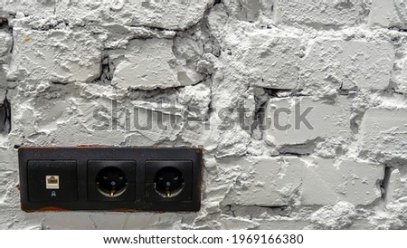 White brick wall with black electrical outlets.