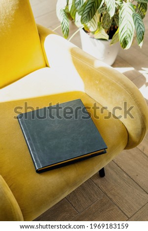 Photo books made of genuine leather cover for storing photos. Stylish diaries for entries for the week. Photo albums and books of literature are lying on a wooden chair.