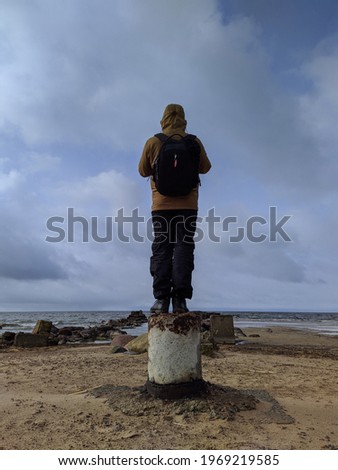 young man photographer taking pictures of the sea landscape back view