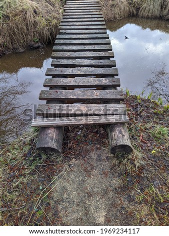 old wooden bridge path across the river in the forest