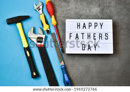 Light box with the inscription HAPPY FATHER'S DAY with construction tools on a gray concrete and blue background. Holiday concept.
Flat lay.