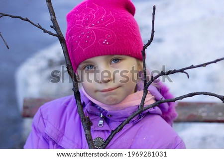 A five-year-old girl stands with birch twigs