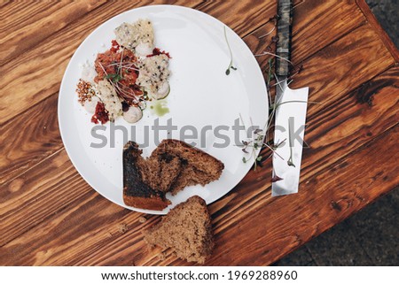Plate with delicious tartare, toasted bread and salad on a wooden table. Healthy gourmet French food made of raw meat.