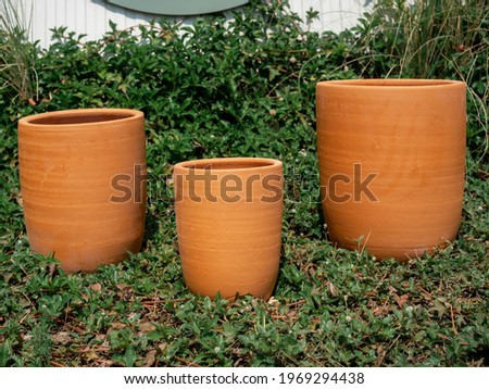 Various size of terracotta plant pots arranged on green grass in the garden. Thre empty terra cotta planter background.