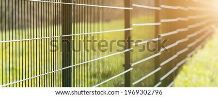 Metal fence leaving in perspective with the sun on grass background