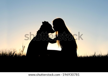 a special and serene moment as a girl is lovingly hugging her German Shepherd Dog, silhouetted against the sunsetting sky Royalty-Free Stock Photo #196930781