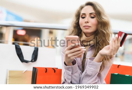 A young woman shopping in an online store pays with a credit card online. Shopaholic concept. High quality photo