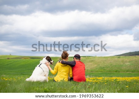 couple with dog relaxing in green spring landscape