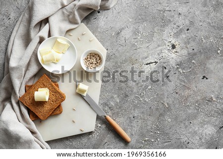 Slices of fresh bread, butter and sunflower seeds on grey background