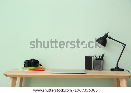 Stylish workplace of photographer near color wall