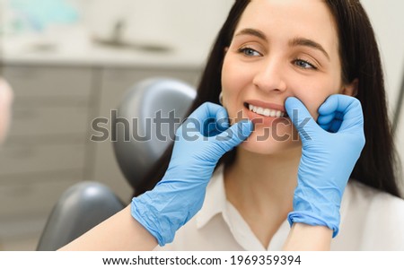 The dentist examines the smile of a young woman after treatment, teeth brushing or enamel whitening. First person close-up shooting