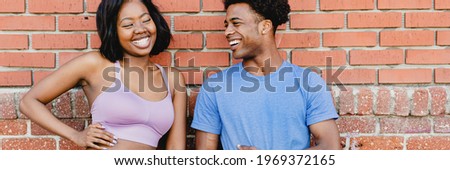 Sporty couple standing by a brick wall
