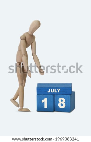 day of the month 18 July calendar A calendar date on blue cubes and a wooden man standing next to it. White background.
