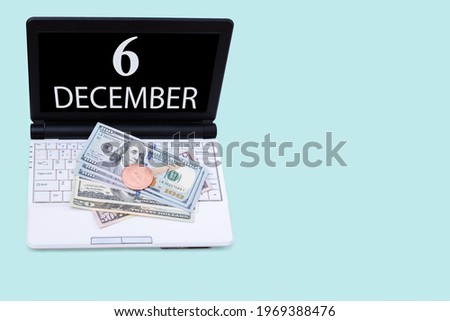 6th day of december. Laptop with the date of 6 december and cryptocurrency Bitcoin, dollars on a blue background. Buy or sell cryptocurrency. Stock market concept. Winter month, day of the year