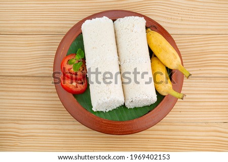 Puttu or White rice puttu -Kerala special breakfast items made using rice flour which is very healthy and arranged in a earthenware with wooden textured  background
