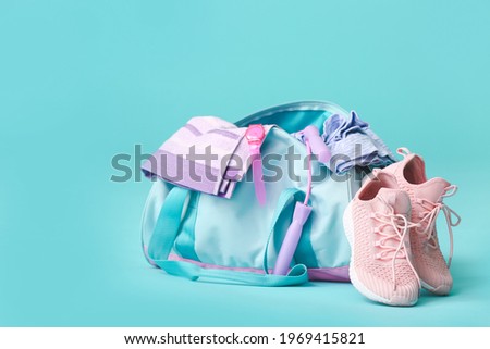Bag with sportswear, equipment and shoes on color background Royalty-Free Stock Photo #1969415821