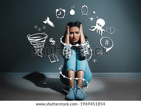 Depressed young woman sitting near dark wall Royalty-Free Stock Photo #1969451854