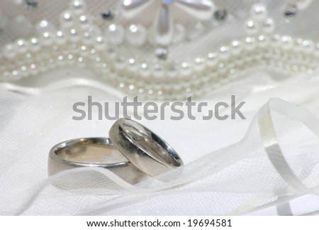 wedding bands sitting on veil with beads