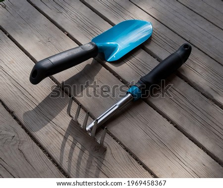Small blue shovel and rake on the wooden floor. Gardener's tools