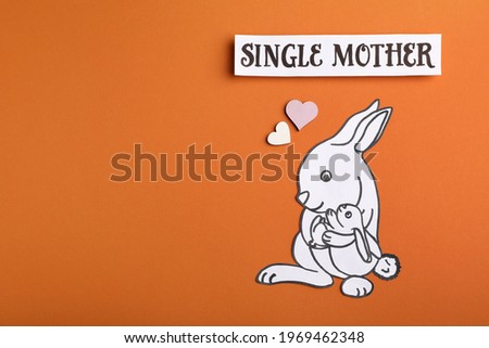 Being single mother concept. Rabbit with baby made of paper on orange background, flat lay and space for text