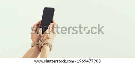 Hands tied with rope on a white background, suggesting internet addiction or social media addiction Royalty-Free Stock Photo #1969477903