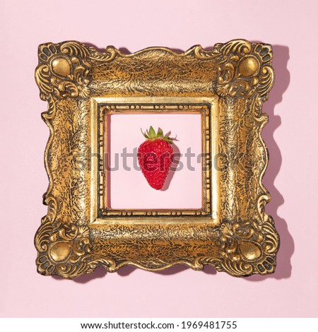 Creative concept with vintage golden painting frame and strawberry on pastel pink background. Minimal summer or spring food or fruit art direction. Flat lay.