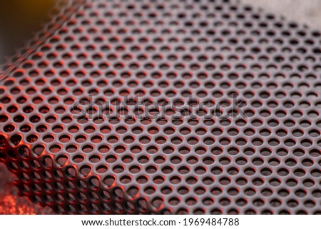 Black ventilation holes of a metal computer case. Aluminum grill close-up.