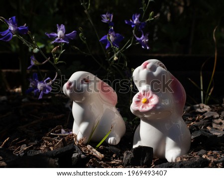 Easter composition with porcelain rabbits in a garden background. Beautiful sunlight. Cute white porcelain rabbit.
