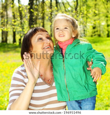 Grandmother has fun with a pretty little granddaughter on the background of yellow dandelions.