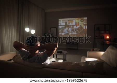 Man watching movie on sofa at night, back view. Space for text Royalty-Free Stock Photo #1969522678