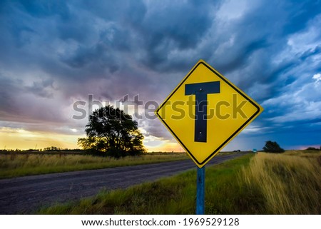 Road crossing warning sign with a stormy sky background, La Pampa province, Patagonia, Argentina.