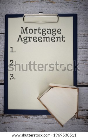 Mortgage Agreement wording with house figure and paper on file. Mortgage concept. Selective focus image.