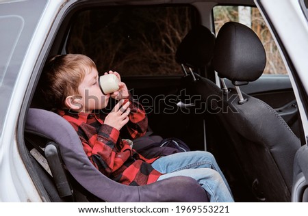 Autotrip with children. Travelling by car. Boy drinks from a cup in the car Royalty-Free Stock Photo #1969553221
