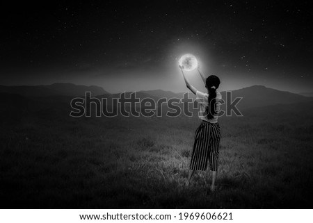 A picture of a little girl standing on the grass with the moon beautifully.