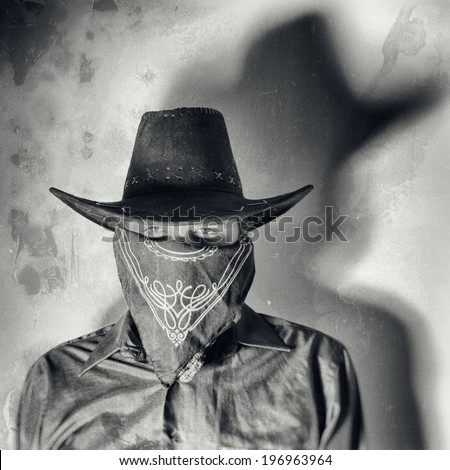 Old West Bandit. Old west bandit outlaw with covered face and cowboy hat, edited in vintage film style. Royalty-Free Stock Photo #196963964