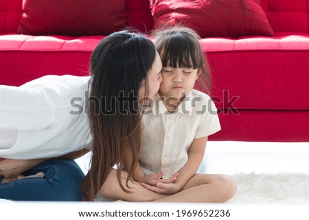 Young mother kiss her child daughter. Mother teach her girl daughter practice family meditation. Mother and  little daughter doing yoga meditate together at home.