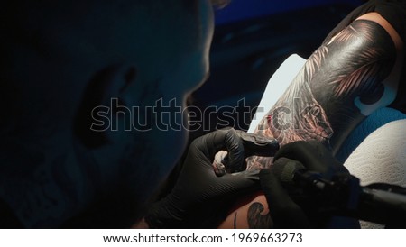 Close up photo of doing black tattoo of snake for woman in studio