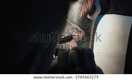 Close up photo of man doing tattoo on woman in studio