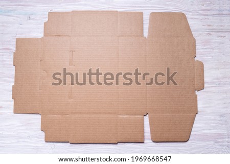 Flat unfolded brown cardboard box on wooden background Royalty-Free Stock Photo #1969668547