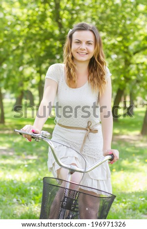 Happy beautiful young woman with bicycle in the park.