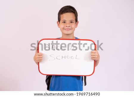 Beautiful young boy smiling holding a white board over white background